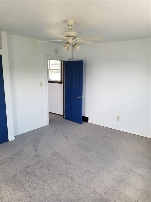 carpeted spare room featuring ceiling fan