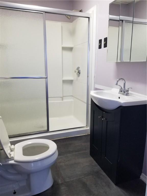 bathroom featuring tile patterned floors, vanity, a shower with shower door, and toilet