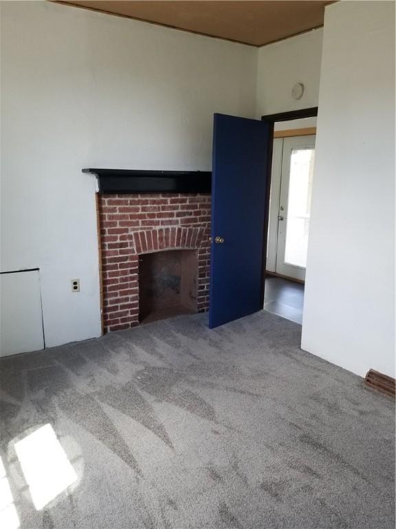 unfurnished living room with carpet floors and a brick fireplace