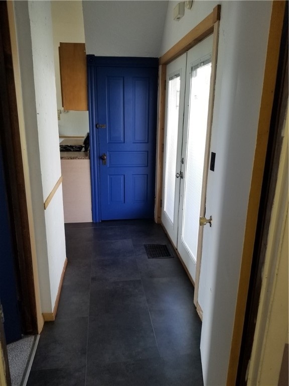 hallway with french doors and dark tile patterned flooring