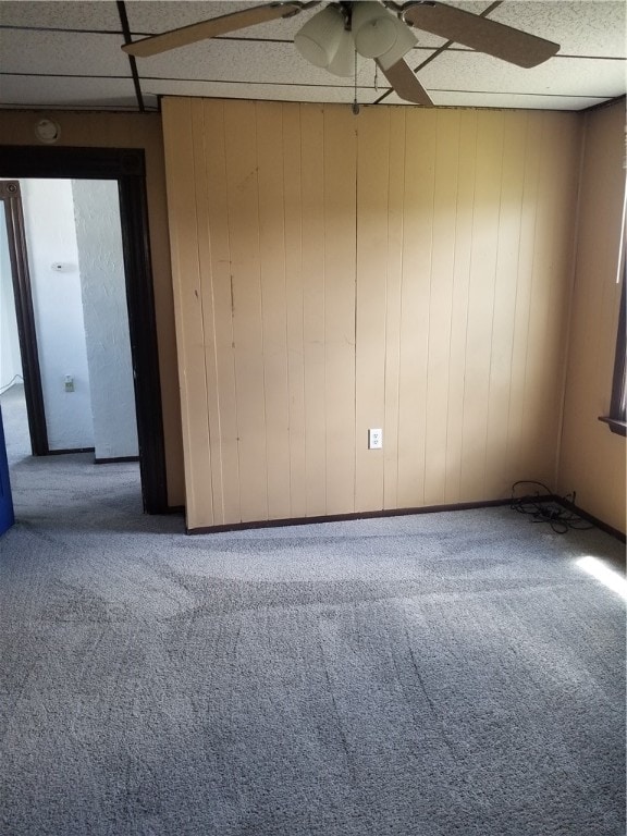 carpeted empty room featuring ceiling fan and a drop ceiling