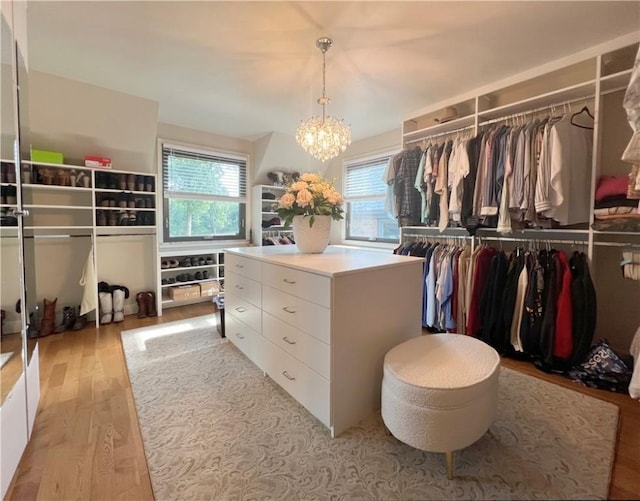 walk in closet featuring light wood-style floors and an inviting chandelier