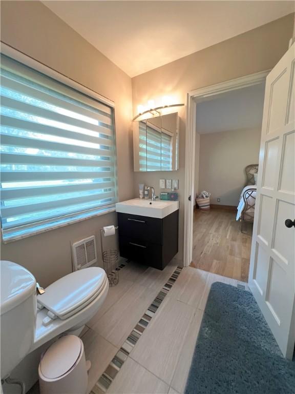 bathroom with visible vents, toilet, ensuite bathroom, vanity, and wood finished floors