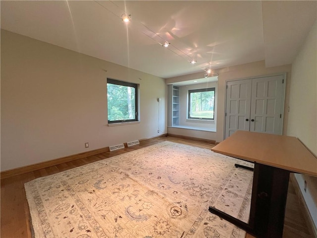 interior space with plenty of natural light, wood finished floors, visible vents, and baseboards