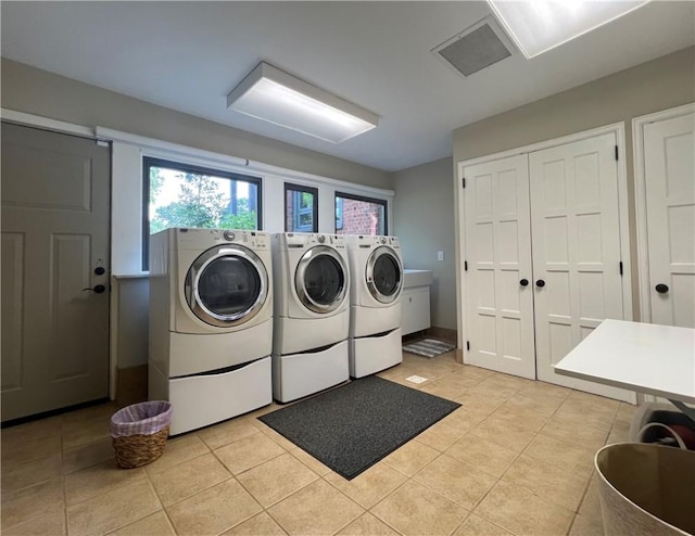 laundry room featuring laundry area, visible vents, light tile patterned flooring, and washing machine and clothes dryer