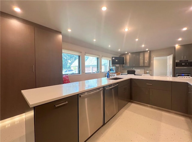 kitchen with appliances with stainless steel finishes, recessed lighting, light countertops, and a sink