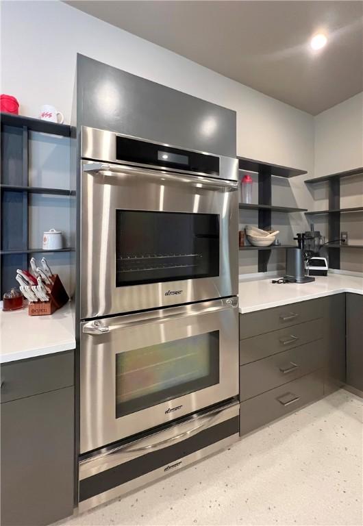 kitchen featuring stainless steel double oven, light countertops, and open shelves