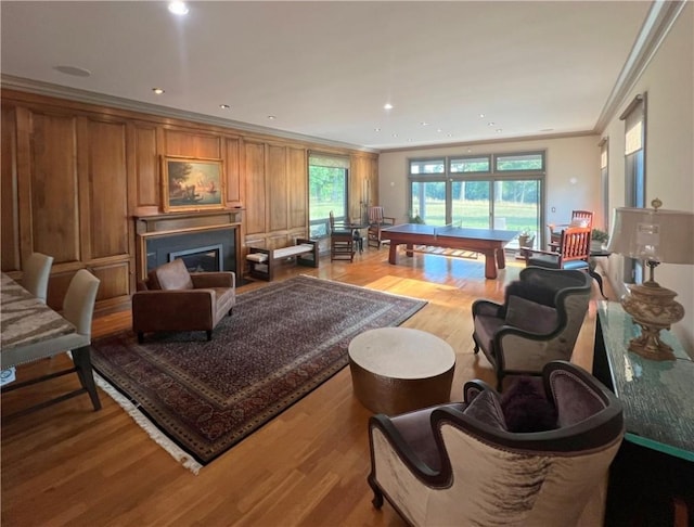 living area with light wood finished floors, recessed lighting, crown molding, and a glass covered fireplace