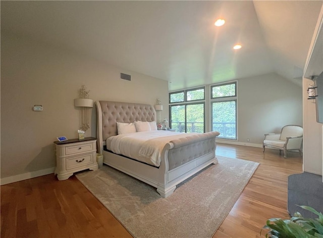 bedroom with vaulted ceiling, baseboards, visible vents, and light wood-style floors