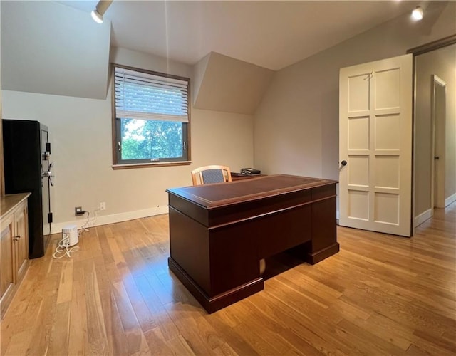 office featuring light wood-style flooring, baseboards, and vaulted ceiling