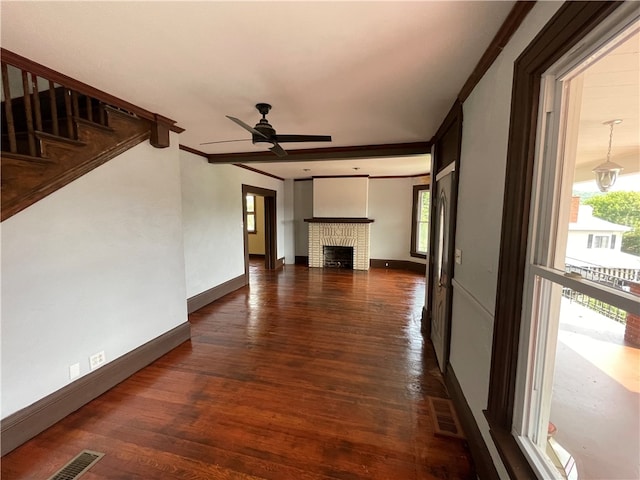 unfurnished living room with ornamental molding, a brick fireplace, dark hardwood / wood-style flooring, and ceiling fan