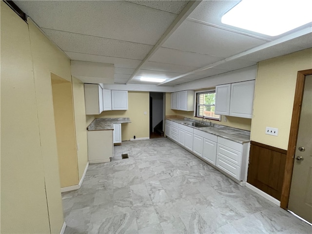 kitchen featuring a paneled ceiling, white cabinets, and light tile patterned floors