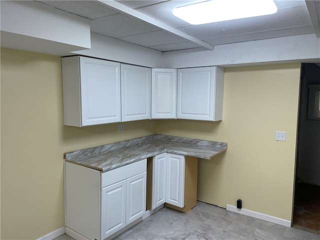 kitchen featuring a drop ceiling, white cabinets, and light tile patterned floors