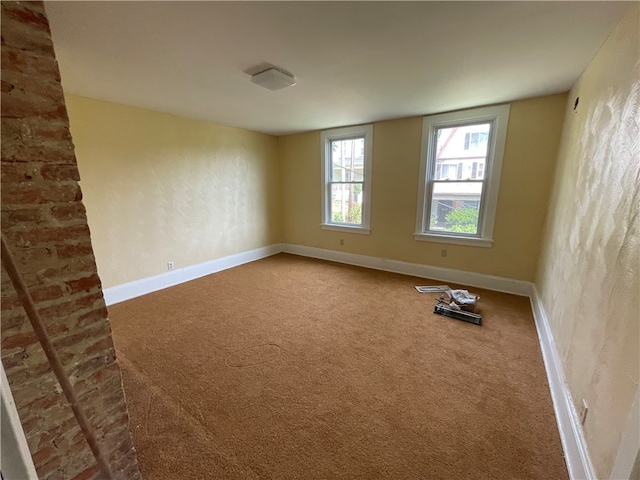 empty room with brick wall and carpet flooring