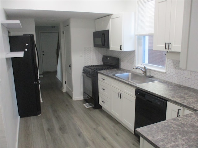 kitchen featuring white cabinetry, black appliances, sink, and hardwood / wood-style floors