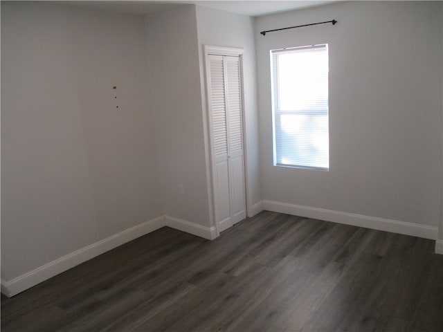 unfurnished bedroom with a closet and dark hardwood / wood-style flooring