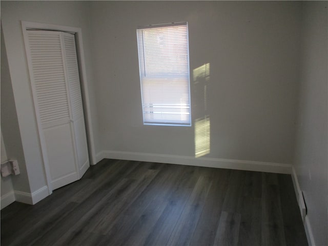 unfurnished bedroom featuring dark hardwood / wood-style floors and a closet