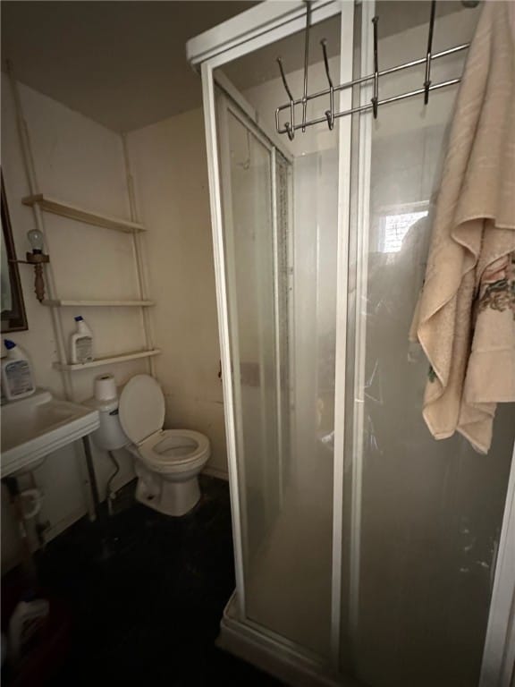 bathroom featuring a shower with door and toilet