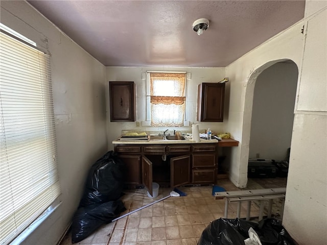 kitchen with sink, a textured ceiling, light tile patterned floors, and dark brown cabinetry