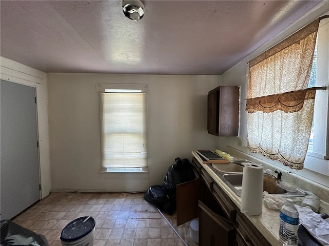 kitchen featuring a textured ceiling, a wealth of natural light, and light tile patterned floors