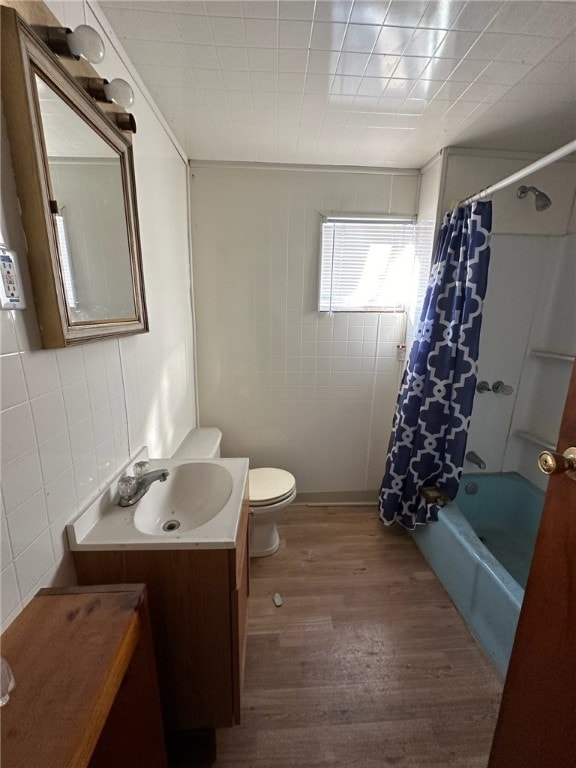 full bathroom featuring shower / tub combo with curtain, vanity, wood-type flooring, tile walls, and toilet