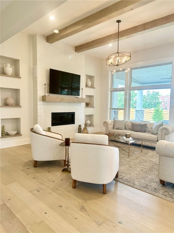 living room with hardwood / wood-style flooring, built in shelves, beam ceiling, and an inviting chandelier