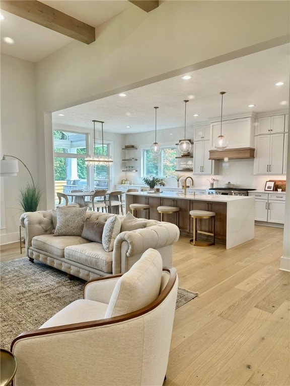 living room with plenty of natural light, beam ceiling, and light wood-type flooring