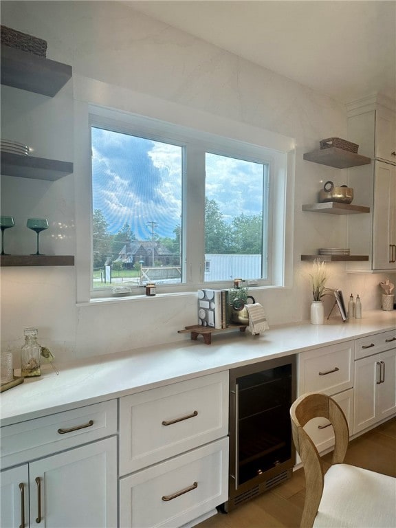 interior space with white cabinets, tasteful backsplash, beverage cooler, and light hardwood / wood-style floors