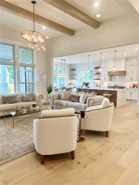 living room with sink, a towering ceiling, light wood-type flooring, and beam ceiling