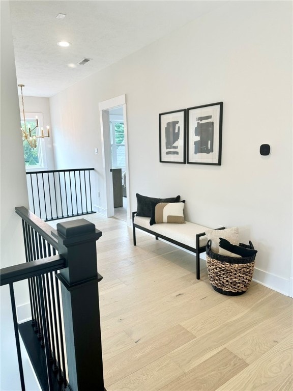 hall featuring a chandelier and light hardwood / wood-style flooring