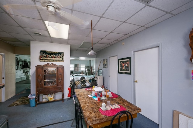 carpeted dining space with a paneled ceiling and ceiling fan