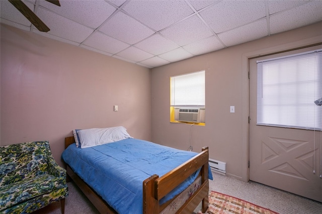 bedroom with a drop ceiling, carpet floors, ceiling fan, baseboard heating, and cooling unit