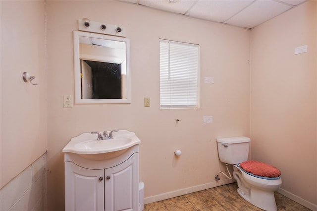 bathroom featuring a drop ceiling, vanity, tile patterned flooring, and toilet