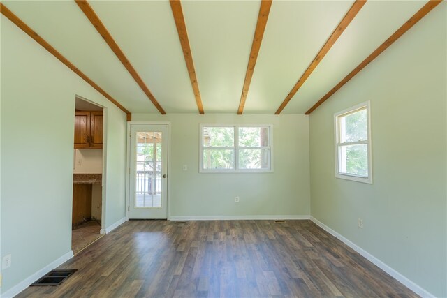 empty room featuring dark wood-type flooring, a healthy amount of sunlight, and lofted ceiling with beams