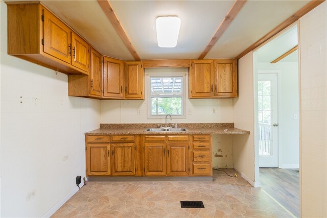 kitchen featuring beamed ceiling, sink, and light wood-type flooring