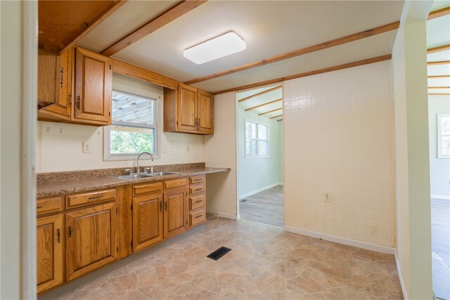 kitchen with beamed ceiling, light wood-type flooring, and sink