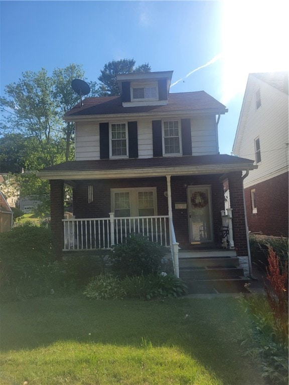 view of front of home with covered porch and a front lawn