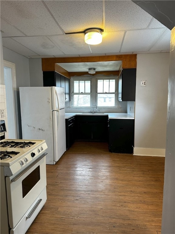 kitchen featuring a paneled ceiling, sink, white appliances, and hardwood / wood-style flooring