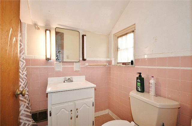 bathroom featuring vanity, tile walls, toilet, and vaulted ceiling