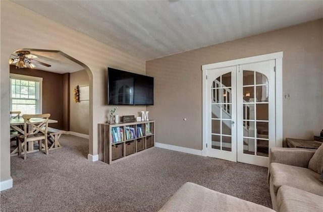 living area featuring carpet, baseboards, arched walkways, and french doors