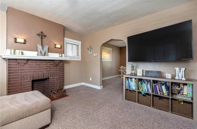 carpeted living area featuring a brick fireplace, baseboards, and arched walkways