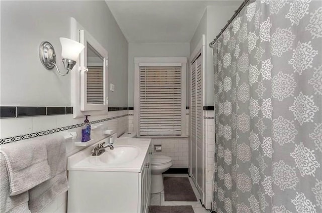 full bath with tile walls, curtained shower, a closet, toilet, and vanity