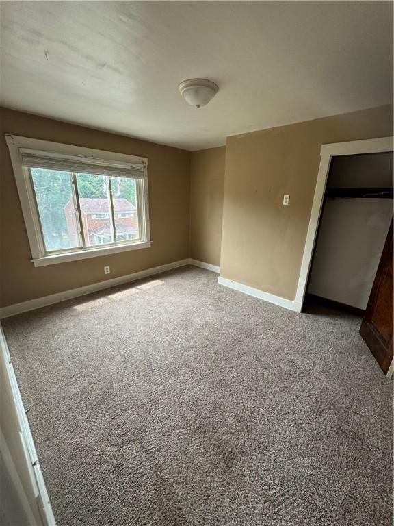 unfurnished bedroom with carpet floors, baseboards, and a closet