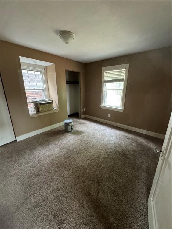 unfurnished bedroom with cooling unit, multiple windows, baseboards, and carpet flooring