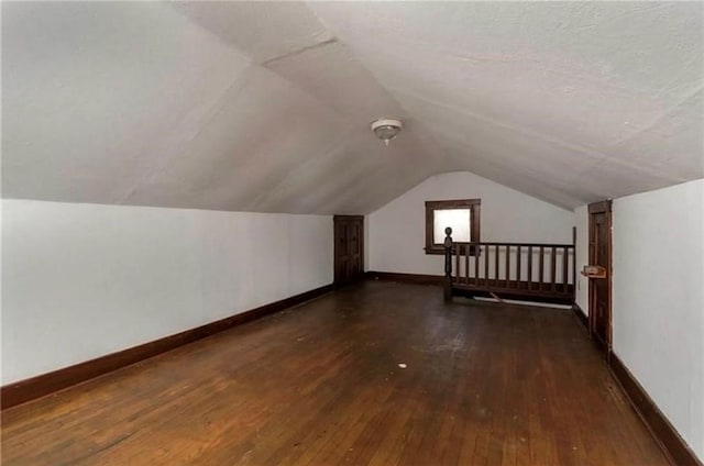 bonus room featuring vaulted ceiling, dark wood finished floors, a textured ceiling, and baseboards