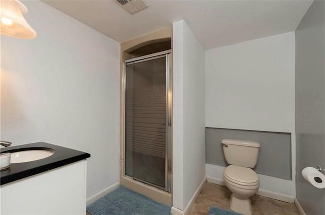 bathroom with toilet, vanity, baseboards, visible vents, and a shower stall