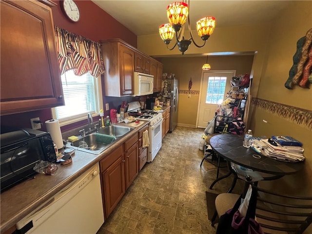 kitchen with white appliances, pendant lighting, a notable chandelier, and sink