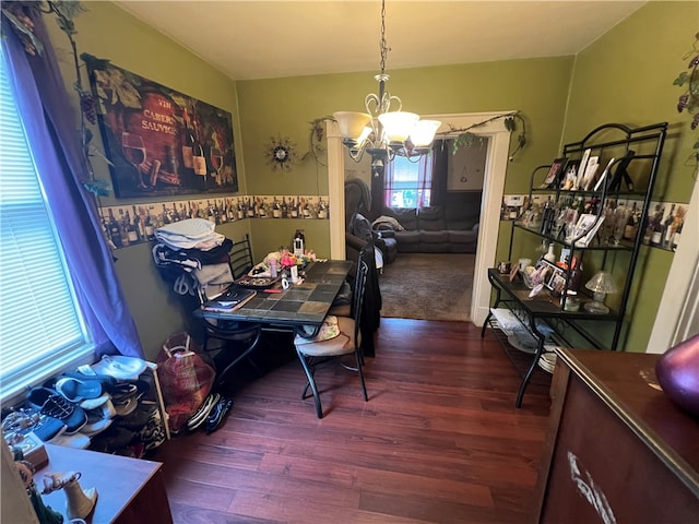 dining area with dark hardwood / wood-style flooring and an inviting chandelier