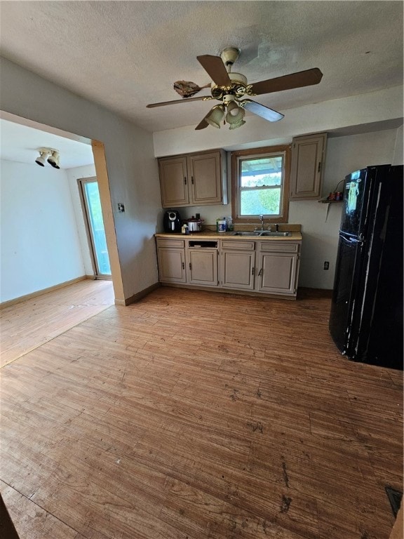 kitchen featuring sink, ceiling fan, black fridge, and light hardwood / wood-style floors