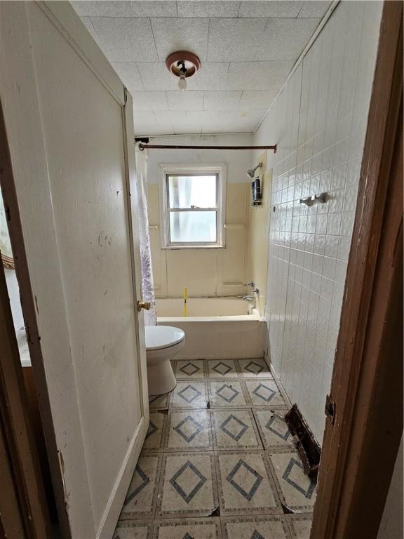 bathroom featuring tile patterned flooring, toilet, and shower / bath combination with curtain